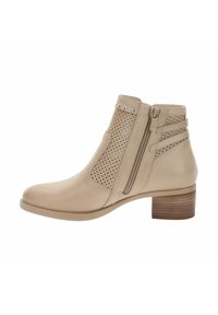 Bota beige hasta el tobillo con paneles de cuero perforados, tachuelas decorativas, cremallera lateral y tacón bajo de madera apilada.