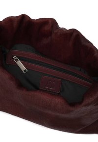 Burgundi műszőrméből készült táska fekete textil béléssel; cipzáras zsebbel és márkázott bőr címkével rendelkezik. Puha tapintású és gyűrött kialakítású.