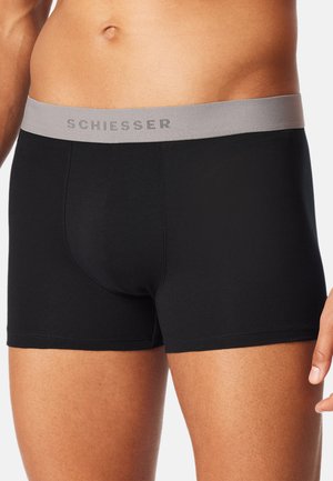 Schwarze Baumwoll-Boxershorts mit einem grauen elastischen Bund, auf dem der Markenname "SCHIESSER" vorne aufgedruckt ist. Einfaches Design und enge Passform.