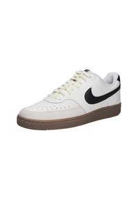 Zapatillas de cuero blancas con un swoosh negro, que cuentan con una suela de goma texturizada en color beige y una puntera perforada para mayor transpirabilidad. Cordones crema incluidos.