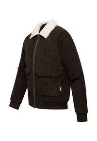 Jachetă din fustă maro cu guler din blană albă, două buzunare frontale, închidere cu fermoar și manșete ribidate. Material texturat cu linii verticale.