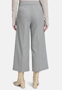 Spodnie o szerokich nogawkach w jasnoszarym materiale, z wykończeniem w stylu dopasowanym i przeszyciami, zestawione z beżowymi botkami na obcasie i miękkim kremowym swetrem.