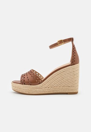 Sandale compensée en cuir marron avec design découpé, bride ajustable à la cheville et talon en jute tressé. Base en fibre naturelle texturée.