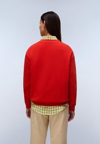 Κόκκινο φούτερ από απαλό υλικό, με πουκάμισο πράσινο-λευκό καρό από κάτω. Το μοντέλο φορά χακι παντελόνι. Πλάγια και πίσω όψη.