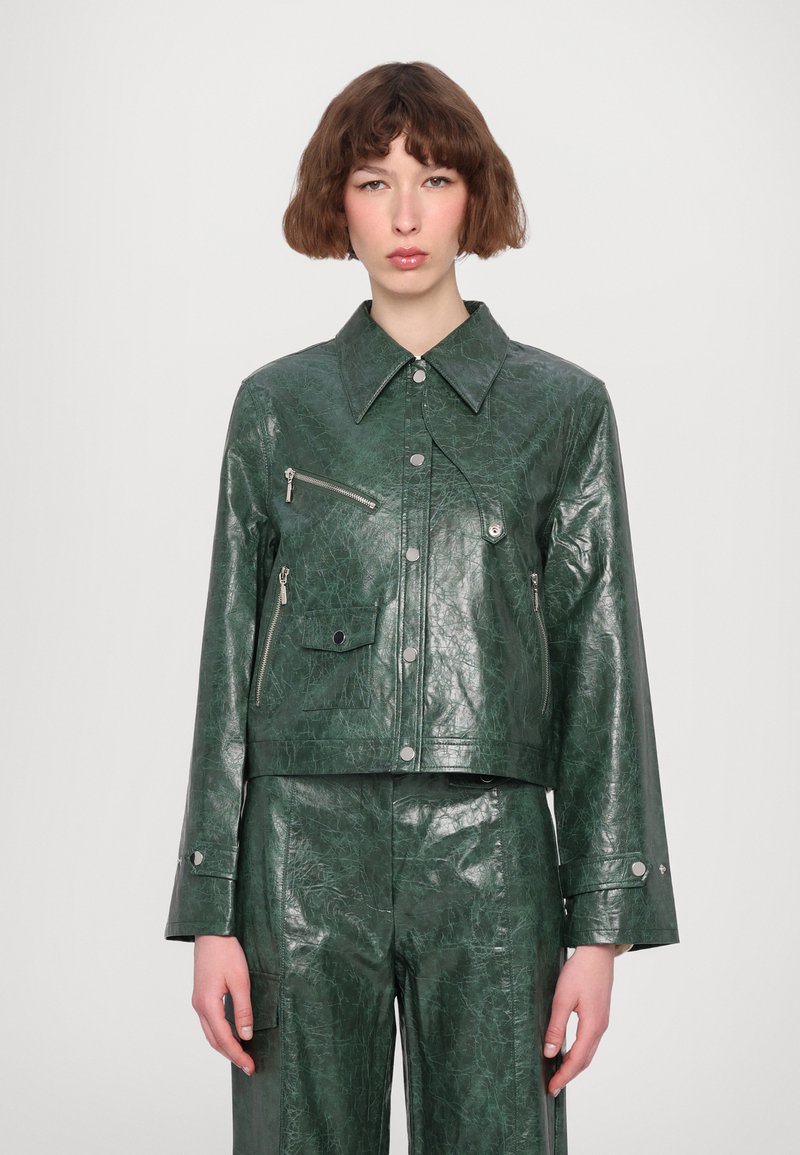 Giacca cropped in ecopelle verde con un ampio colletto, accessori in metallo argentato, tasche con zip davanti e una texture screpolata. Maniche lunghe.