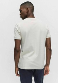 Herrarnas kortärmade, ljusgrå t-shirt i mjuk bomull. Slimmat snitt med rund hals och slät textur. Inga mönster eller dekorationer.