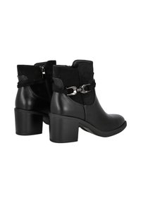 Botas de tobillo de cuero negro con tacón cuadrado, con una parte superior de ante, cierre de cremallera y un acento decorativo de cadena metálica en el costado.
