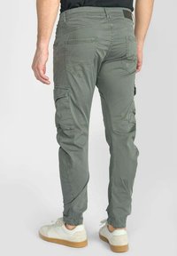 Groene cargobroek met meerdere zijzakken, elastische manchetten en een relaxte pasvorm. Gemaakt van een lichte, textuurrijke katoenmix.