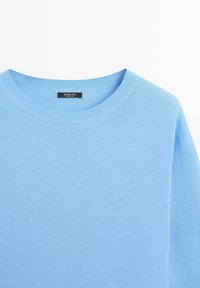 Lichtblauwe trui met korte mouwen en een ronde hals met duidelijk zichtbare geribbelde kraag en een Massimo Dutti-label aan de binnenkant van de halslijn.