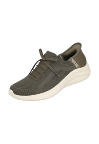 Zapatilla deportiva verde oscuro con parte superior de tejido texturizado, cordones planos y suela blanca. Presenta un cuello acolchado y detalles de malla en el lateral.