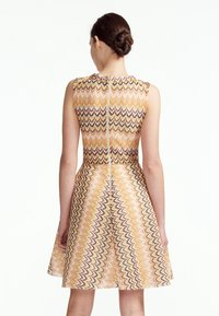 Abito senza maniche con un motivo a zigzag in giallo, rosa e nero, con un corpino aderente e una gonna svasata, chiusura con zip sul retro centrale.