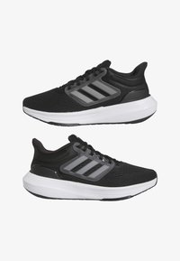 Sneakers atletici neri con una tomaia in mesh testurizzata, tre strisce grigie sui lati e una suola intermedia bianca. Presentano un collare imbottito e lacci.
