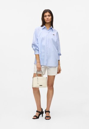 Zils un balts svītrainas, pārmēru lielas krekls, balti šorti, melnas papēžu sandales un krēmkrāsas rokassomiņa ar sudraba detaļām.