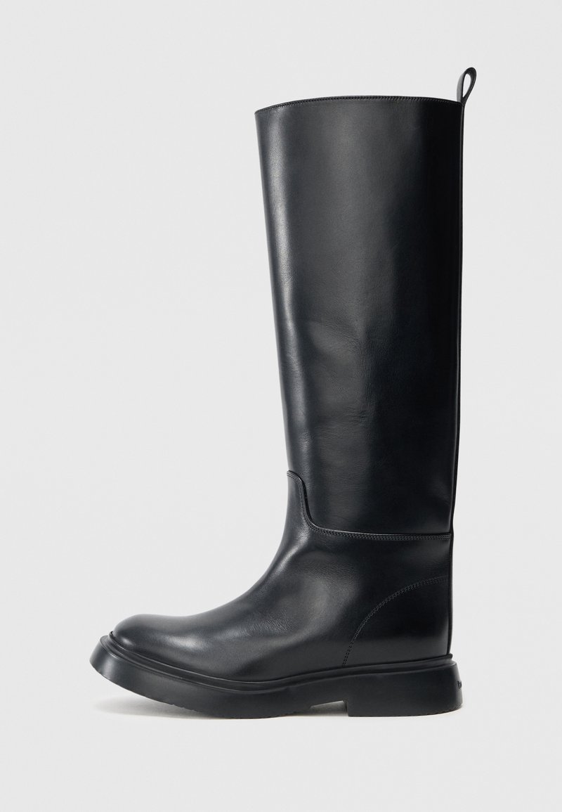 Ψηλές μαύρες δερμάτινες μπότες με λεία επιφάνεια, στρογγυλεμένη μύτη και επίπεδη λαστιχένια σόλα. Διαθέτουν πίσω ταινία για εύκολη εφαρμογή.