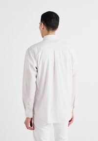 Light gray long-sleeve shirt with white vertical stripes. Features a standard collar and buttoned cuffs. Smooth fabric texture.