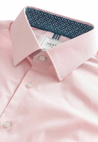 Helles rosa Hemd mit einem strukturierten Kragen, ausgestattet mit einer blauen gemusterten Innenfütterung, zwei Perlmuttknöpfen und einem Etikett mit der Aufschrift "NEXT Tailored."