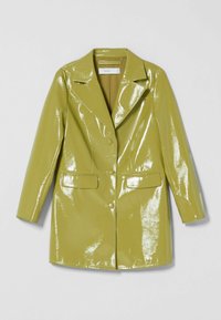 Glanzende vinyl jas in olijfgroen met een opstaande kraag, twee zakken aan de voorkant en een knoopsluiting. Gladde textuur met een glanzende afwerking.