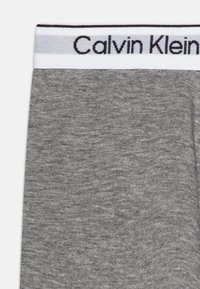 Sivý bavlnený pás s logom "Calvin Klein" v čiernej farbe. Hladký povrch s jemným melírovaným vzorom.