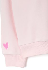 Sudadera rosa con puños acanalados. Presenta un pequeño corazón bordado en rosa más oscuro en la manga. Textura de tela suave, diseño casual.