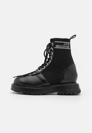 Bottine noire à cheville avec semelle épaisse, tige en maille côtelée, lacets à l’avant, et logo "LOVE MOSCHINO" près du bord supérieur.