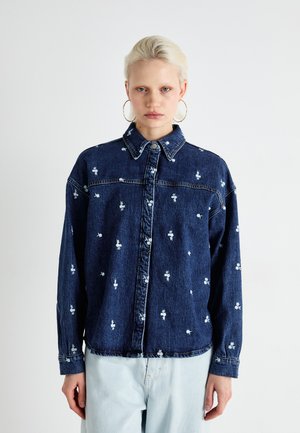 Denim shirt in dark blue, featuring white floral embroidery, button-up front, classic collar, and long sleeves with button cuffs.