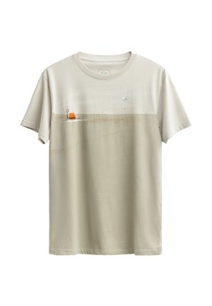 T-shirt en coton beige avec un imprimé minimaliste de scène de plage, featuring une chaise orange, un cercle rouge et des accents bleu clair. Manches courtes, encolure ronde.