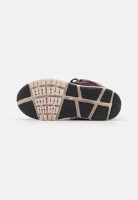 Sneakerzool met zwarte rubberen grip met een gestructureerd patroon, lichtbruine tussenzool en flexibele groeven voor een verbeterde grip.