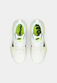 Bijele mrežaste tenisice za trčanje s neonsko žutim naglascima i crnim brendingom, koje imaju teksturirani gornji dio, vezice te podstavljeni jezik i ovratnik.