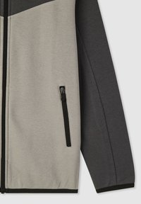 Giacca in fleece con tasca con zip, blocchi di colore grigio e grigio scuro, texture liscia e polsi elastici lungo il fondo e le maniche.