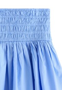 Gonna azzurra chiara con cintura elastica arricciata. Realizzata in un tessuto liscio e dalla consistenza morbida, presenta pieghe fluenti su tutta la superficie.