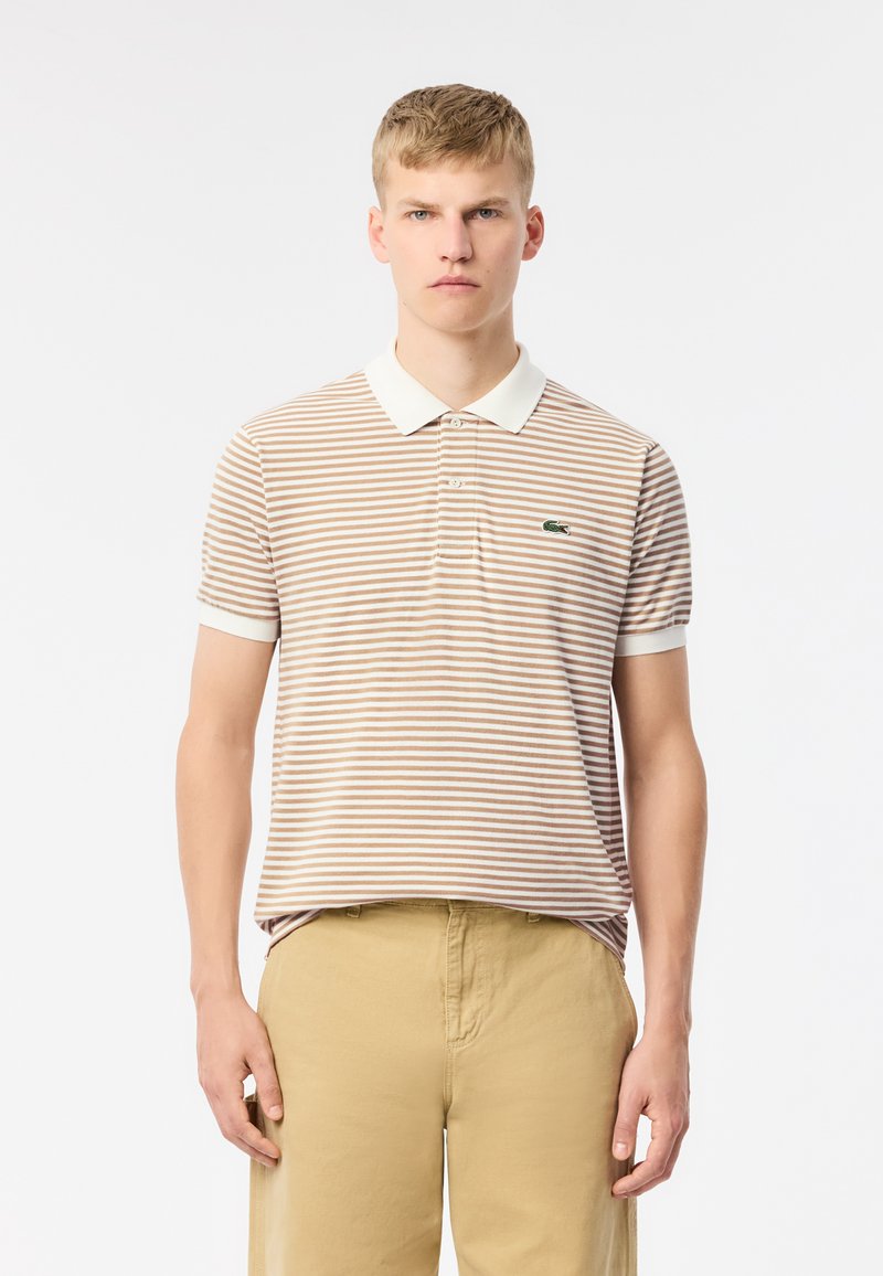 Polo à manches courtes beige avec des rayures crème, doté d'un col classique et d'un logo vert sur la poitrine gauche. Matériau en coton durable.