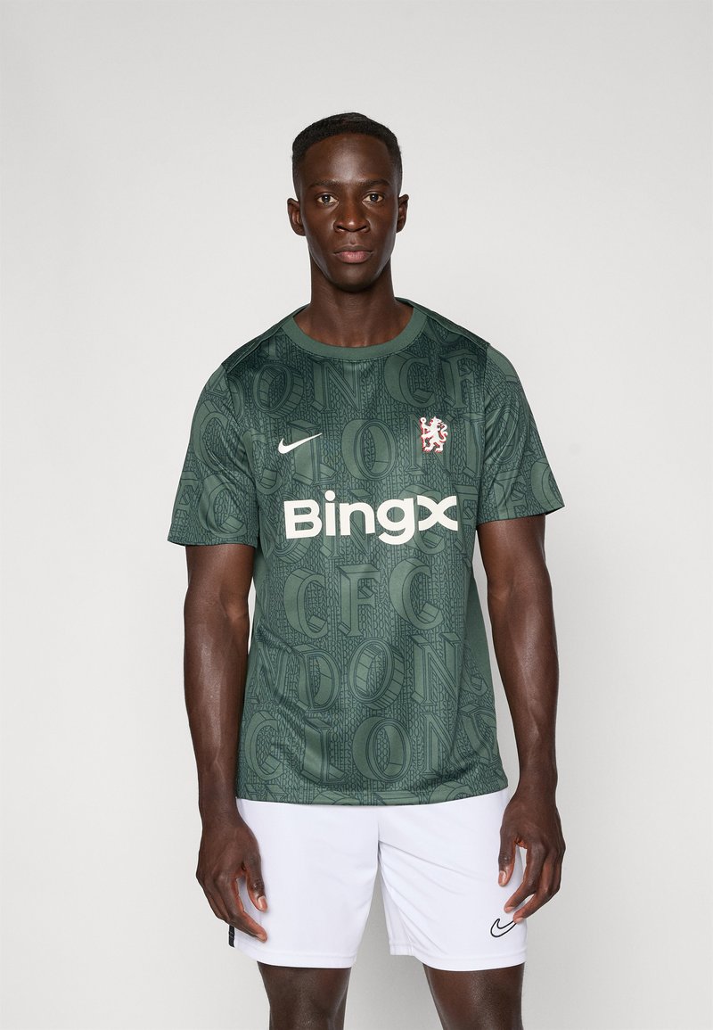 Camisola verde escura com um padrão texturizado, logotipo da Nike em branco e a marca "Bingx"; emparelhada com calções brancos.