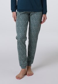 Pantaloni da pigiama in stampa leopardata di colore teal con polsini elastici e tessuto elasticizzato. Presentano un piccolo motivo di accento rosa su tutta la superficie.