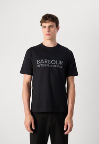 T-shirt preta em algodão com decote redondo, mangas curtas e logótipo "BARBOUR INTERNATIONAL" em uma impressão texturada e contrastante.