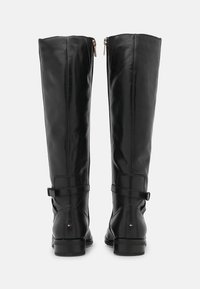 Stivali in pelle nera al ginocchio con una texture liscia, chiusura con zip posteriore e dettagli con fibbie. Tacco spesso e logo del marchio sul tacco.