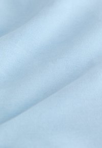 Tissu bleu clair avec une texture lisse et des plis doux, montrant un détail fin de tricot.