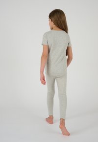 Camisa de manga corta gris melange y leggings a juego, ambos hechos de una tela suave; diseño ajustado con una textura lisa, sin patrones visibles.