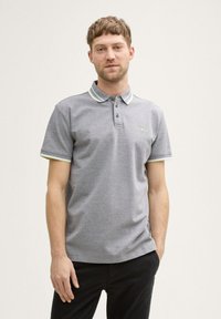 Graues Polohemd mit einem zwei-knopfigen Ausschnitt, kontrastierendem Kragen und Ärmelsäumen in Hellgrün. Kurze Ärmel, glatte Stofftextur.