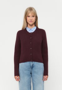 Gilet bordeaux en tricot doux, avec un col en V, des manches longues et six boutons noirs sur le devant.