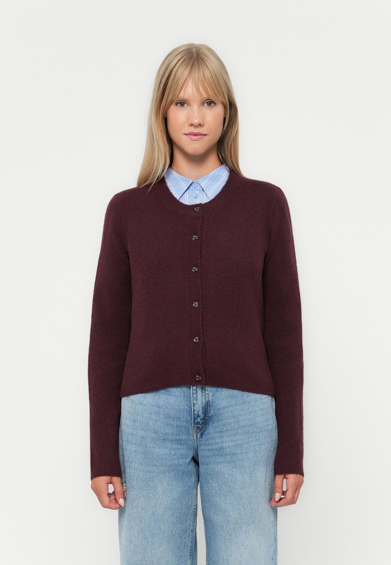 Gilet bordeaux en tricot doux, avec un col en V, des manches longues et six boutons noirs sur le devant.
