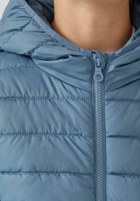 Himmelblauer, plüschiger Jacke mit Reißverschluss, verstellbarem Kapuzen und horizontalem Steppmuster. Glatter, strukturierten Stoff mit eleganter Oberfläche.