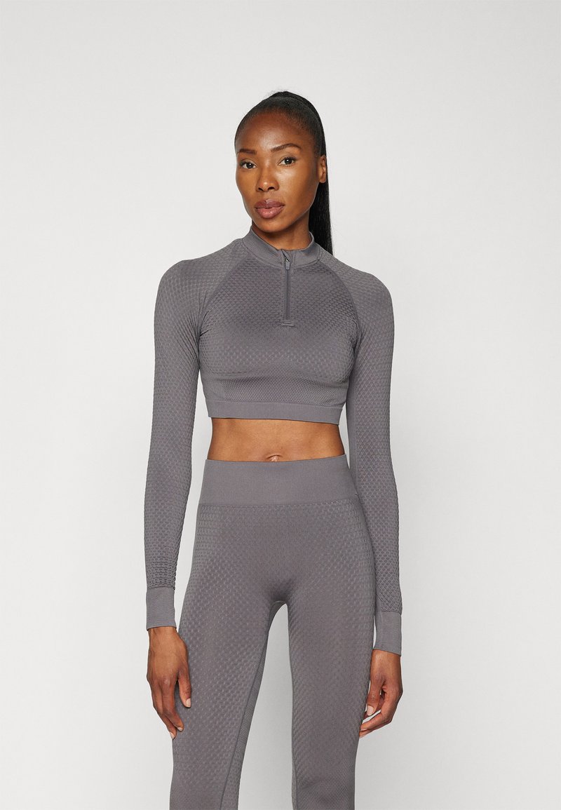 Gray athletic crop top and matching high-waisted leggings with a textured pattern, long sleeves, and a quarter-zip neckline.