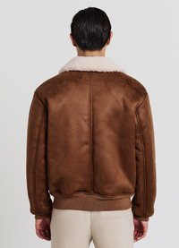 Giacca in finta pelle scamosciata marrone con colletto in shearling color crema, polsini e orlo a coste, caratterizzata da una texture liscia e una vestibilità rilassata.
