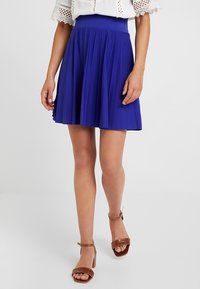 Pleated skater skirt in vibrant blue, made of lightweight fabric. Features a high waistband and a flared design that extends to mid-thigh.