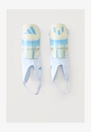Par de espinilleras Adidas de Messi en azul y blanco con correas elásticas para el tobillo sobre un fondo liso.