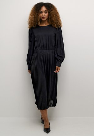 Black pleated dress with long puff sleeves, elastic waistband, and a smooth texture. Mid-calf length with a classic round neckline.