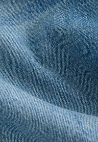 Denim tkanina svijetloplave boje, s glatkom teksturom i izraženim dijagonalnim rebrastim uzorkom, karakterističnim za tipične denim tkanine.