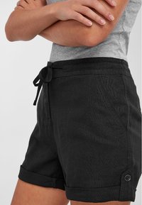 Shorts neri in lino con vita regolabile tramite cordoncino, risvolti, tasche laterali e una finitura texture. Presentano dettagli in contrasto con bottoni.