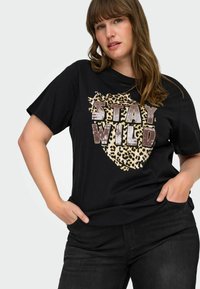 Black short-sleeve t-shirt featuring a leopard print graphic and "STAY WILD" text in metallic gold and black accents.