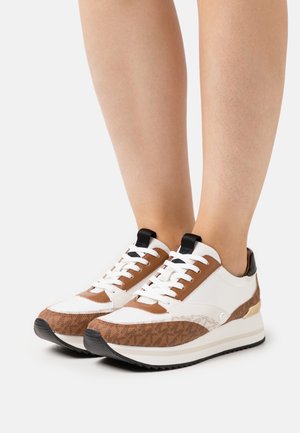 White and brown sneakers with a patterned brown accent, black trim, and white laces. Features a chunky sole and padded collar.